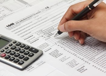 Person completing 1040 tax form with calculator